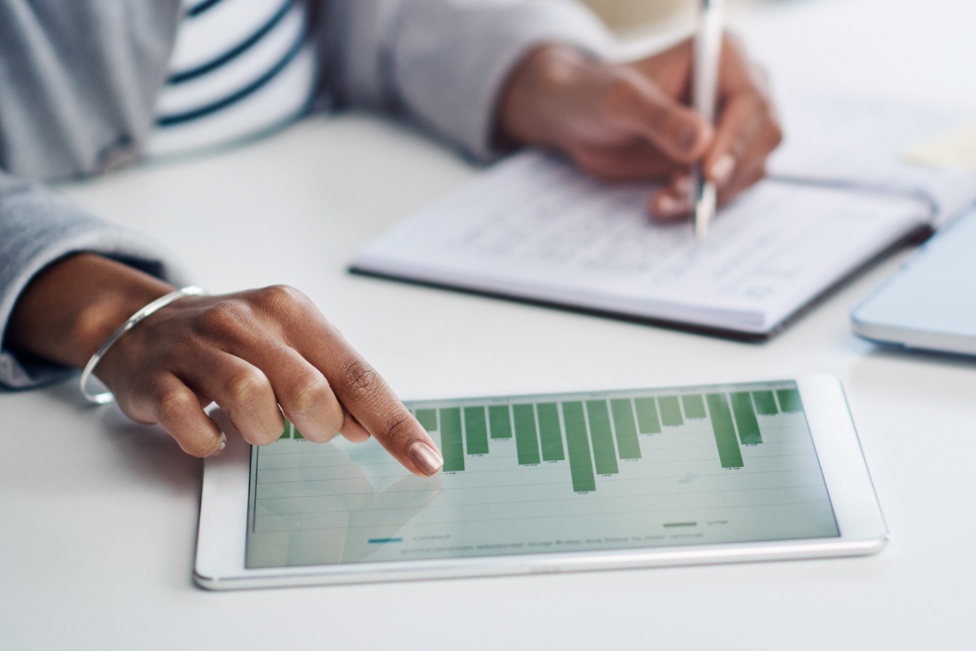 Close-up of woman at a desk working on notes while reading a chart.