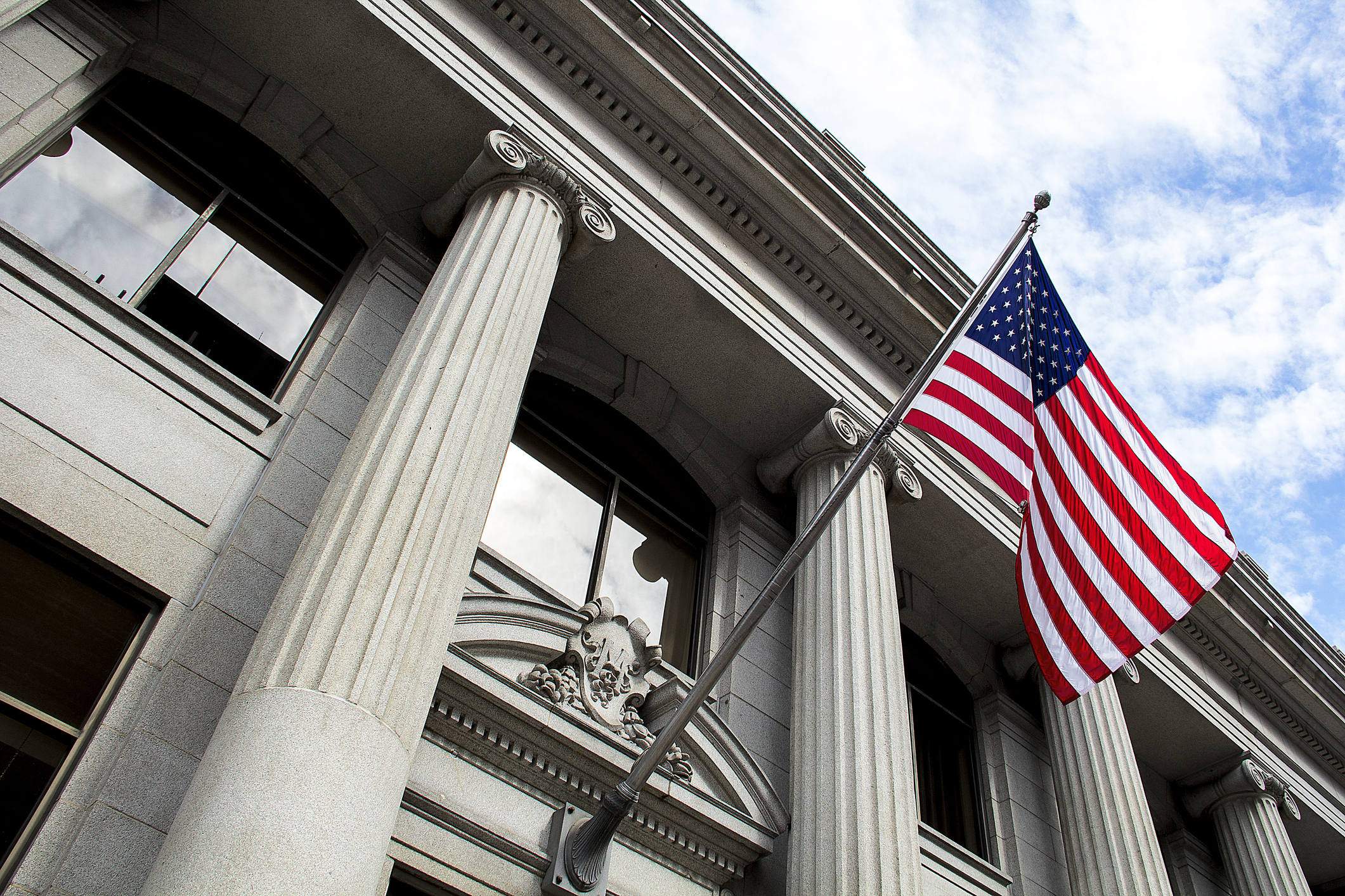 Outside view of the front of a government building with American flag waving.