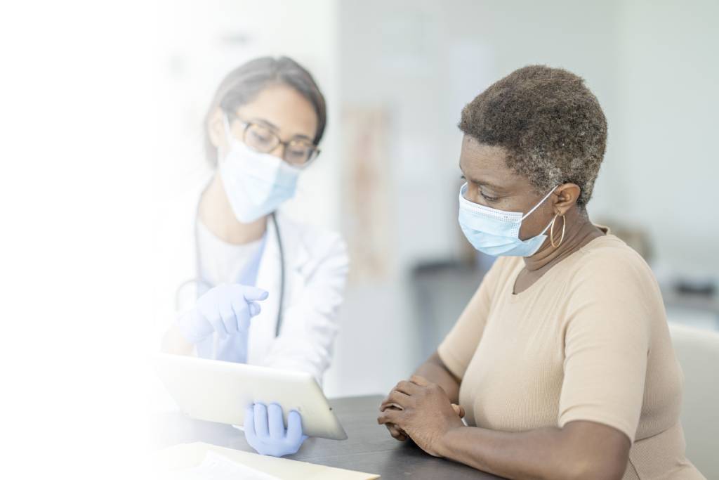 Woman reviewing tablet with doctor