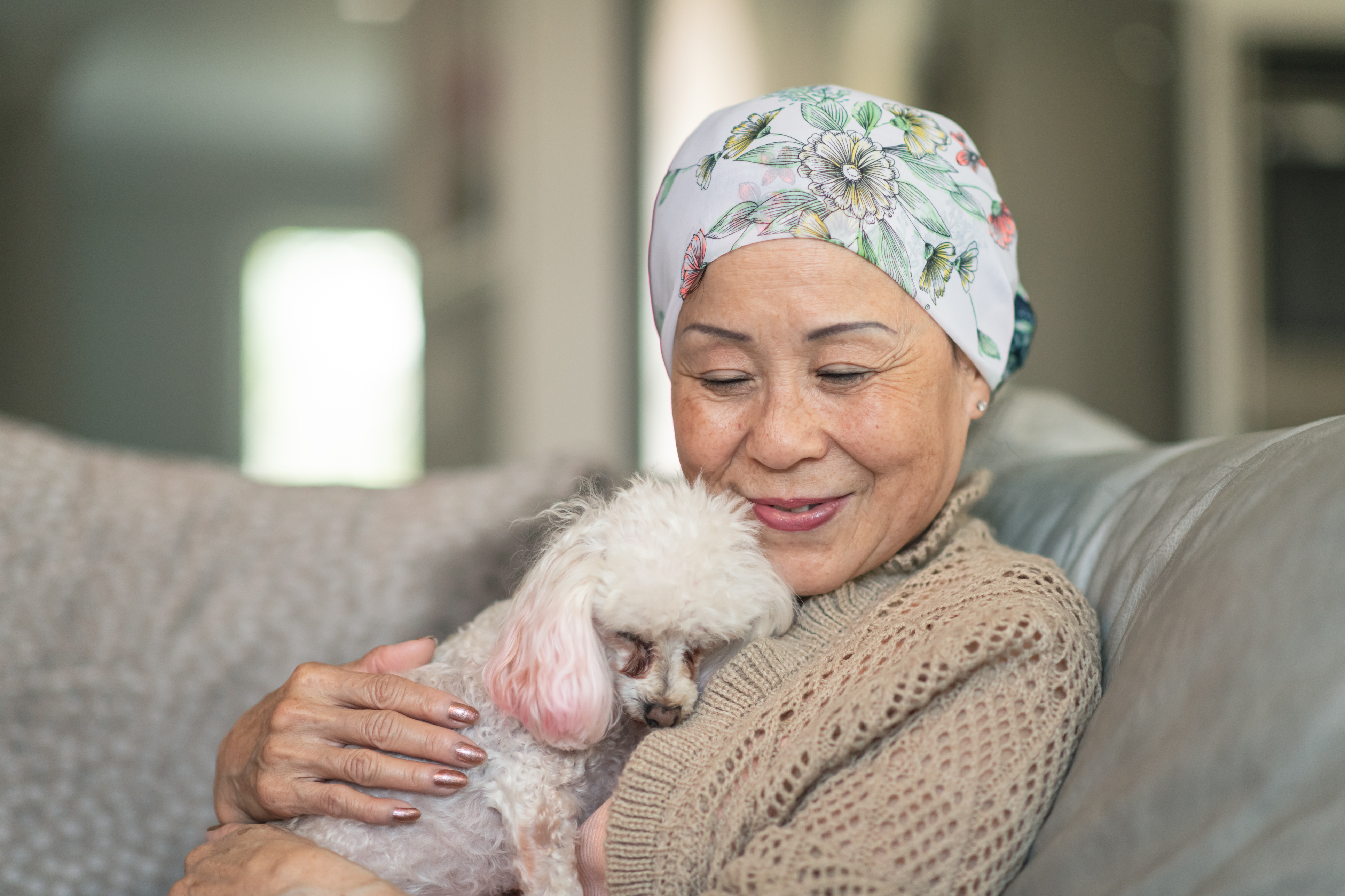 Woman holding small dog on couch