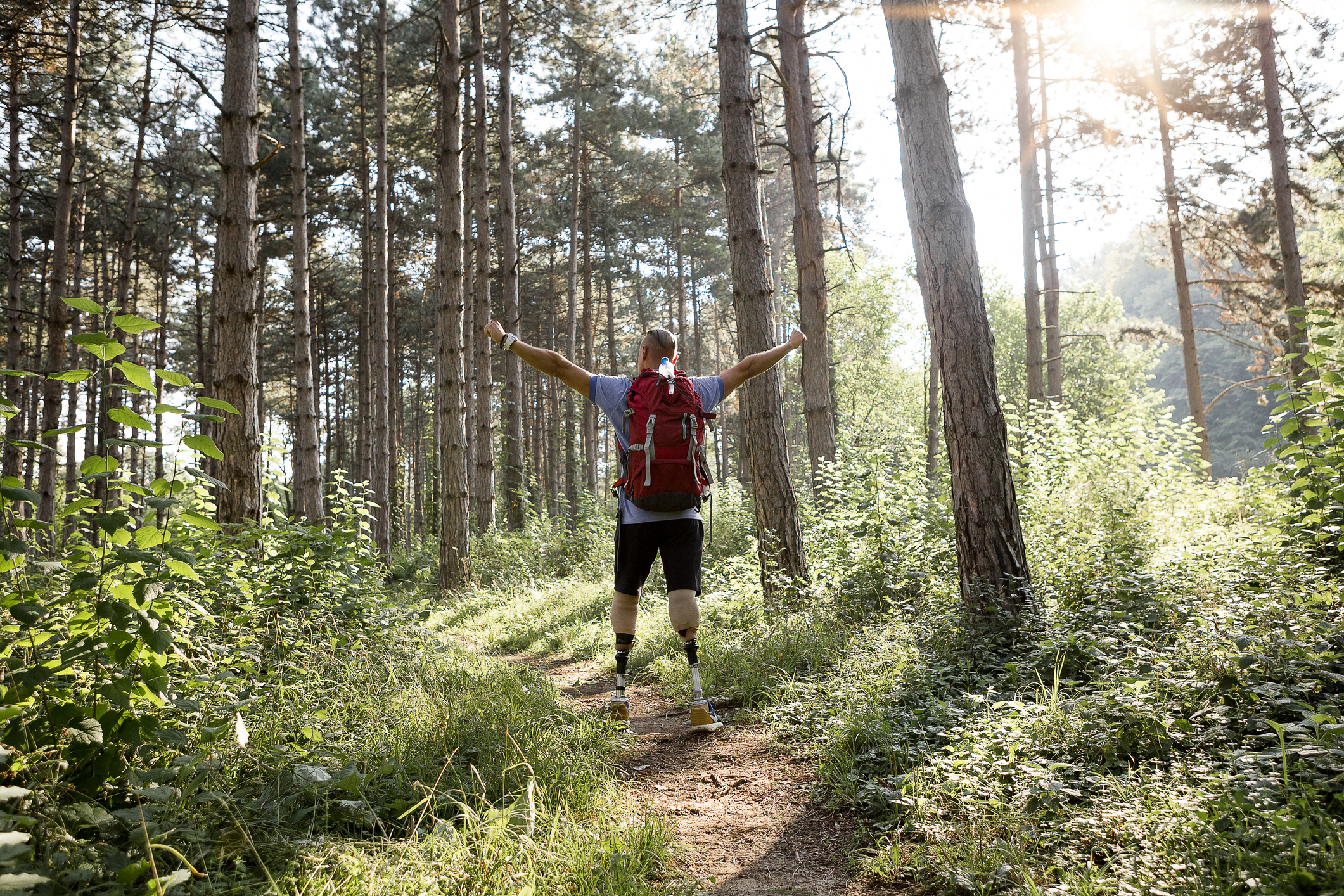 Man with prosthetic legs hiking in a forest.