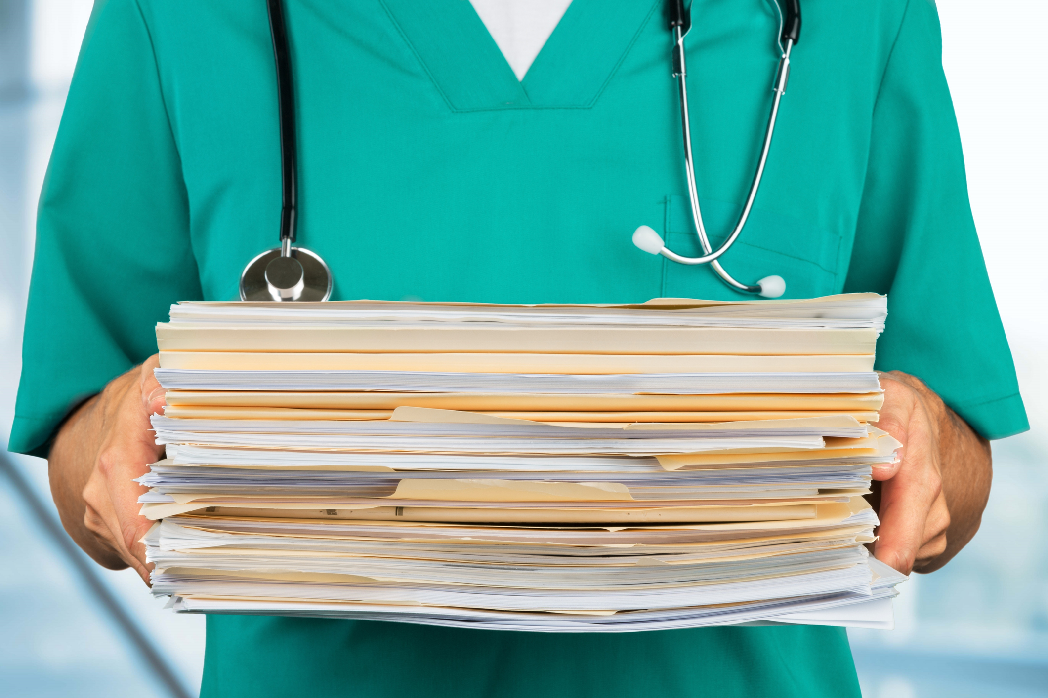 Close-up of a stack of medical files being held by a doctor.