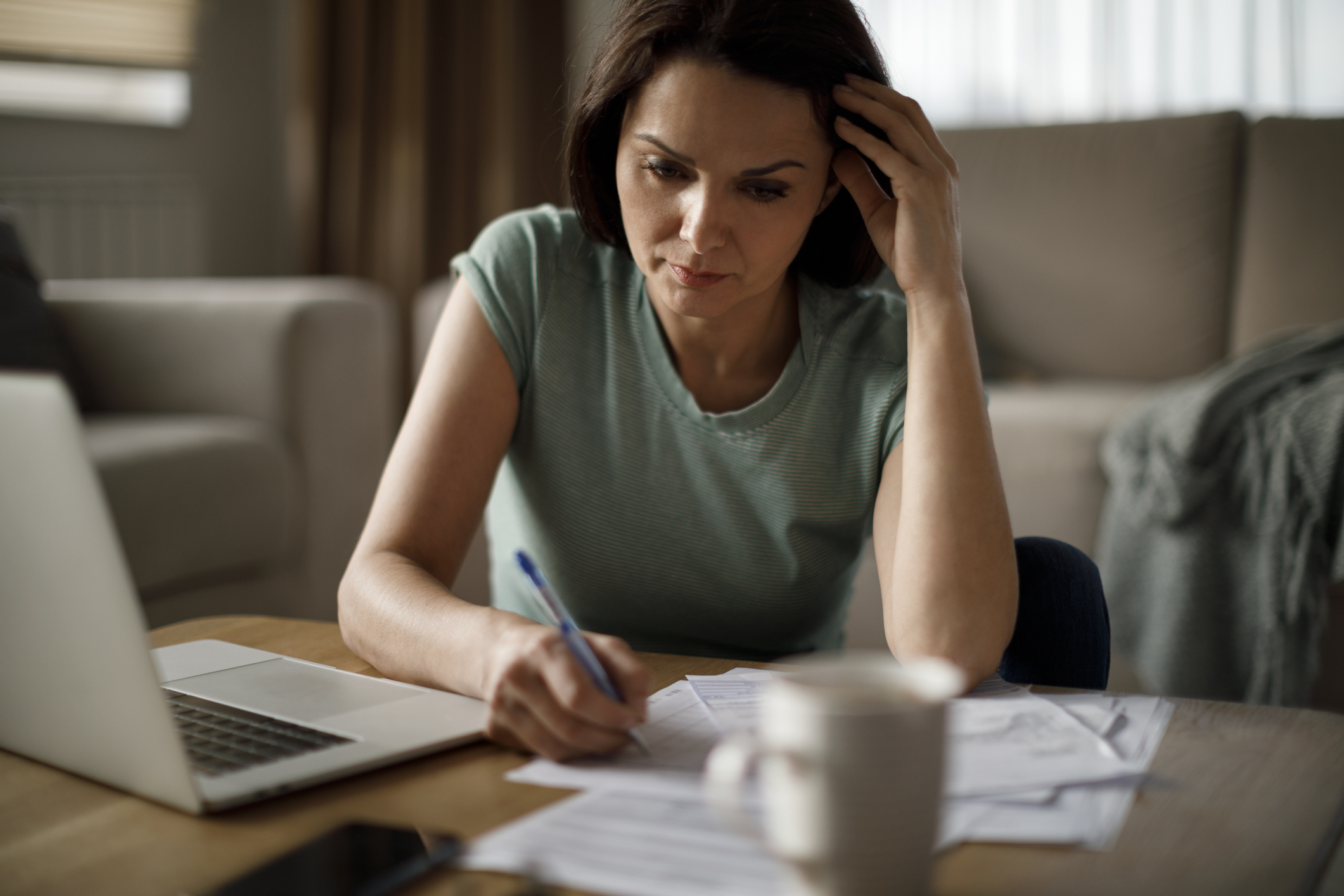Woman concentrating while working on an application at her coffee table at home.
