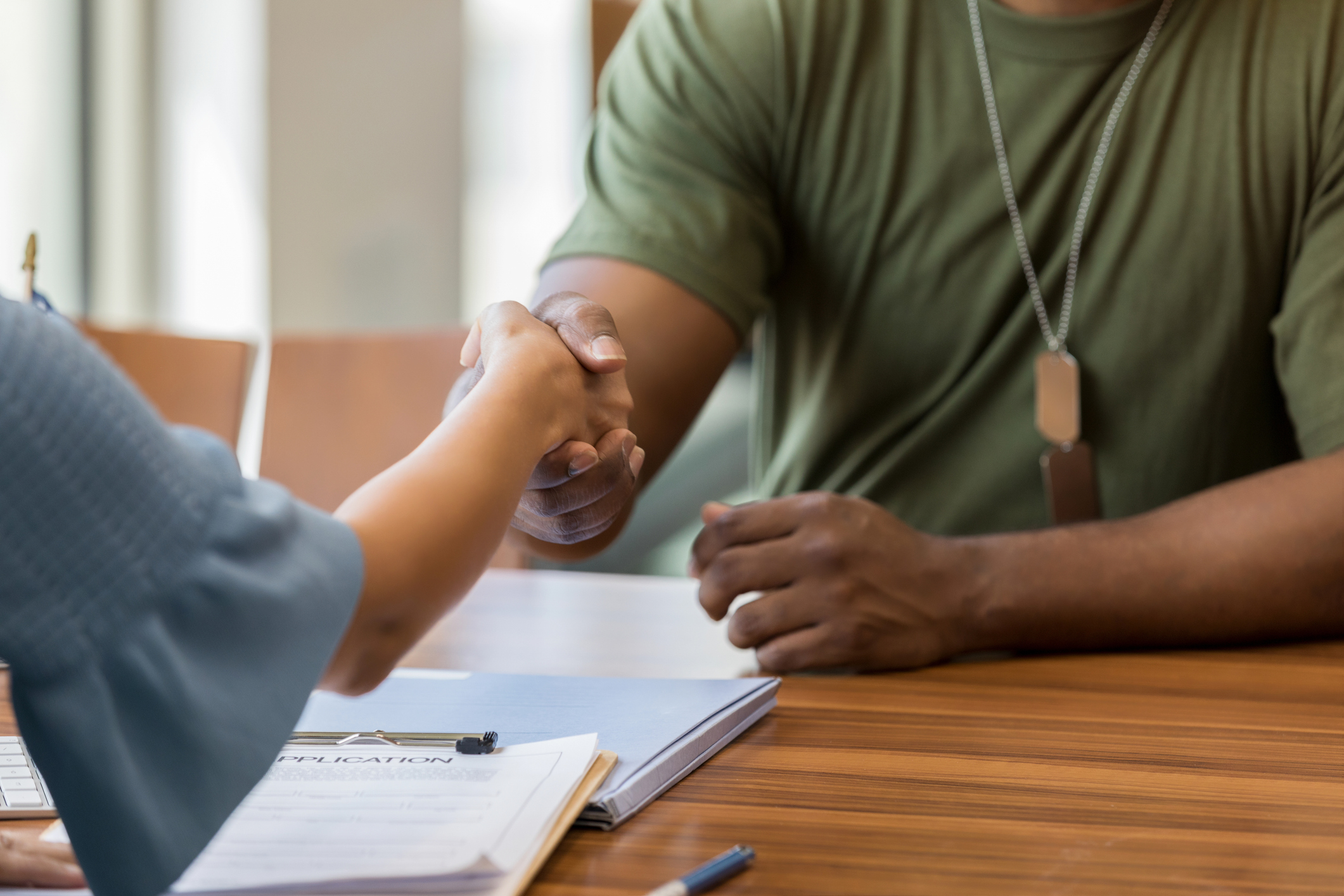 Man shaking woman's hand across a desk.